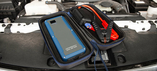 Rover 3600A portable jump starter with red and black jumper cables stored in its case inside a car engine bay.