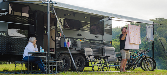Caravan campsite with awning clothesline, couple relaxing outdoors and hanging washing.