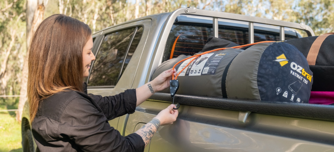 Woman securing an OZtrail Fatmat 750 in a ute with a bungee