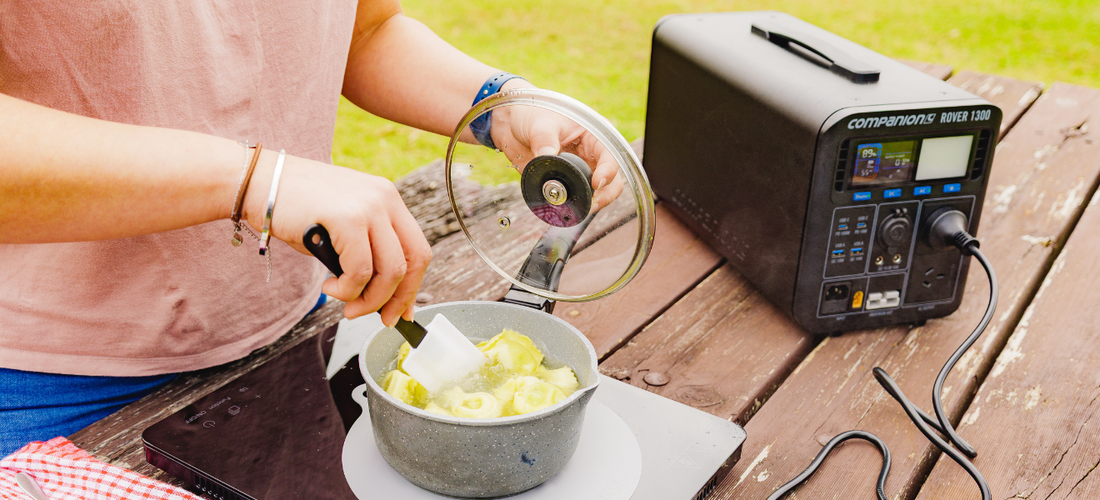 Person cooking on induction cooktop powered by Rover 1300 portable power station outdoors