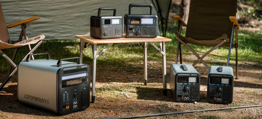 Companion Rover X3 and X6 power stations on a camp table, with the Rover X24, X15 and X15 MAX on the ground at a campsite